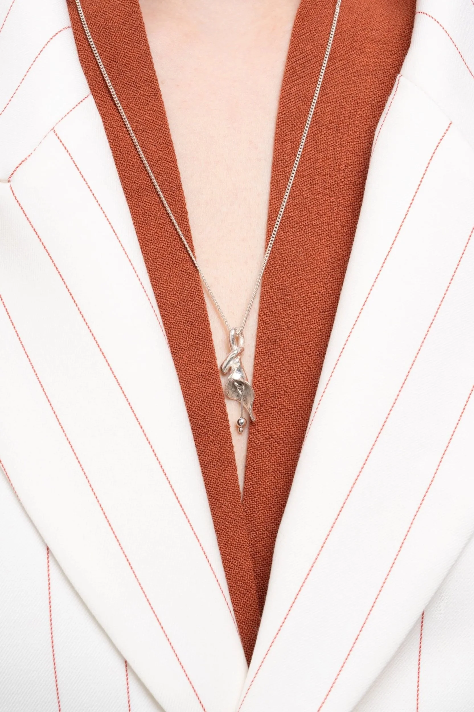 Necklace detail photographed against a white coat